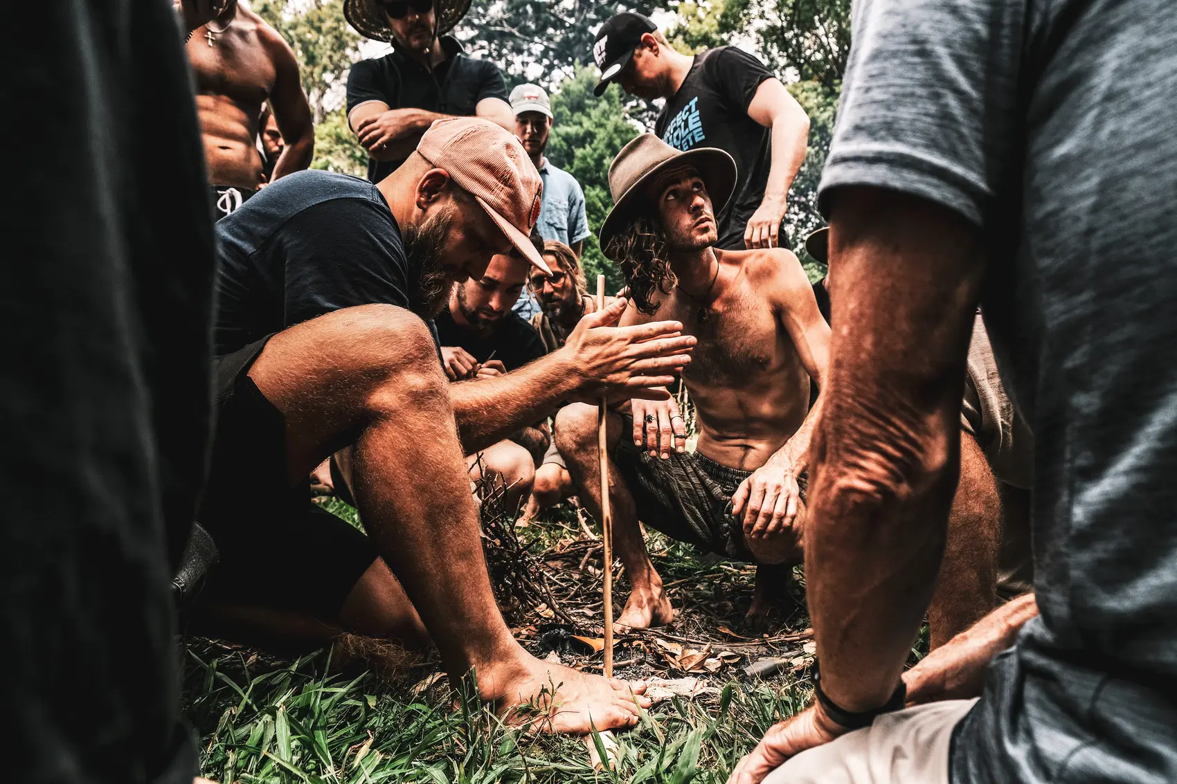 A man held by his brothers in the firelight as he does the work